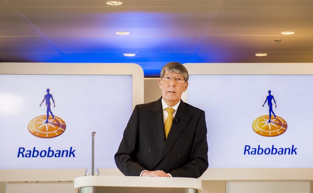 Rabobank houdt rekening met een beperkt negatief effect op de winst van het handelsconflict met Rusland. De grootste bank van Nederland heeft veel klanten in de agrarische sector. Dat maakte Rabobank donderdag bekend bij de presentatie van de cijfers over de eerste helft van 2014. Rabobank stelt dat een aantal van zijn zakelijke klanten gevoelig is voor de deze maand afgekondigde Russische boycot van agrarische producten uit de Europese Unie. Lees meer daarover in dit artikel. Voor de tweede jaarhelft houdt Rabobank voor zichzelf dan ook rekening met een beperkte negatieve invloed hiervan op de eigen resultaten. Agrarische kredieten Rabobank Rabobank is een belangrijke financier van de agrarische sector en zag de omvang van de kredietportefeuille Food- en Agrisector in de eerste helft van dit jaar met 2 procent stijgen tot 88,5 miljard euro. Hiervan heeft 31,8 miljard euro betrekking op kredieten in Nederland en 56,7 miljard euro aan kredieten buiten Nederland. Internationaal is Rabobank vooral sterk actief in de Verenigde Staten, Australië, Nieuw-Zeeland en Brazilië met agrifinanciering. Bankenheffing overheid drukt winst Rabobank Rabobank behaalde in de eerste helft van dit jaar een nettowinst van bijna 1,1 miljard euro, 3 procent minder vergeleken met dezelfde periode vorig jaar. De winst werd met 214 miljoen euro gedrukt door een eenmalige heffing van de Nederlandse overheid voor de bankensector in verband met de nationalisatie van SNS Reaal. Bij de binnenlandse kredietverlening hadden zakelijke klanten het relatief zwaar in de eerste helft van dit jaar. Dit was af te lezen aan de voorzieningen voor zwakke leningen die uitkwamen op 0,54 procent van de gemiddelde kredietportefeuille, tegen 0,49 procent in de eerste helft van 2013. Het langjarig gemiddelde ligt volgens Rabobank op een veel lager niveau van 0,32 procent van de kredietportefeuille. Zwakke kredieten vastgoed en glastuinbouw De zwakte in het bedrijfsleven was vooral merkbaar op de kantorenmarkt en in de glastuinbouw, gelet op de voorzieningen die Rabobank moest nemen voor kredieten in deze sectoren. Bij het onderdeel Rabo Vastgoedgroep wordt flink gesneden, onder meer bij de afbouw van projectontwikkelaar MAB. Het verlies bij dit onderdeel kwam in de eerste jaarhelft uit op 90 miljoen euro, tegen verliezen van 189 miljoen euro in de eerste helft van 2013. Forse aflossing hypotheken, marktaandeel Rabobank daalt Op de particuliere markt in Nederland zag Rabobank de omvang van de totale hypotheekportefeuille met bijna drie miljard euro dalen tot 207,6 miljard euro. Dit had vooral te maken met de trend van hogere aflossingen door huiseigenaren. "In verband met de restschuldproblematiek en lage spaarrentes heeft een gedeelte van de klanten gekozen voor vervroegd aflossen. Hierbij speelde ook de mogelijkheid mee om tot 100.000 euro belastingvrij te mogen schenken, wanneer de ontvanger de schenking gebruikt voor hypotheekaflossing van de eigen woning." Per saldo zag Rabobank zijn marktaandeel op de hypotheekmarkt fors dalen naar 20,1 procent in de eerste helft van dit jaar, tegen 26 procent in de eerste helft van 2013. De lokale Rabobanken waren goed voor een marktaandeel van 15,9 procent (was: 19,2 procent) en dochter Obivon kwam uit op een marktpositie van 4,2 procent (was 6,6 procent). Kwaliteit hypotheekportefeuille Extra aflossingen en een stabilisatie van de huizenprijzen zorgden wel voor een kleine verbetering van de kwaliteit van de hypotheekportefeuille. De verhouding tussen de gemiddelde hoogte van hypotheekleningen en de waarde van woningen daalde namelijk licht, van 80,7 procent in de eerste helft van 2013 naar 79,4 procent in de eerste helft van dit jaar. Van Rabobank's hypotheekportefeuille bestaat 20,6 procent uit hypotheken die zijn gefinancierd met de NHG-regeling. Die beschermt banken als huiseigenaren die in de problemen komen, een restschuld overhouden. Van het deel van de hypotheekportefeuille dat zonder NHG-garantie is gefinancierd, staat ongeveer 20 procent onder water. Dat wil zeggen dat bij deze leningen de hoogte van de hypotheeklening hoger is dan de waarde van de woning. Lees ook Landbouweconoom: alternatief Russische markt geen appeltje-eitje