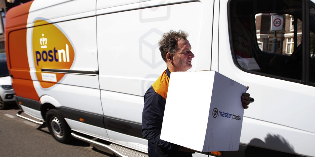 Een postbezorger doet een contactloze bezorging. Bij PostNL is het deze dagen aanzienlijk drukker dan voor de coronacrisis.