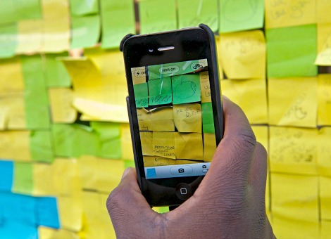 Post-it, het bekende gele kleefbriefje, gaat digitaal. Daarmee hoopt maker 3M een jonge generatie internetgebruikers aan zich te binden. Maar de concurrentie op het gebied van notitie-apps is moordend. De Post-it briefjes, wie kent ze niet. De handige gele briefjes met kleefstrip zijn uitgegroeid tot ware kantoorvrienden, maar vaak dienen ze ook als geheugensteuntje op de koelkast of in de gezinsadministratie. Daarmee zijn ze bijna onmisbaar geworden voor een grote groep mensen. En dat terwijl de briefjes bij toeval zijn uitgevonden. Onderzoeker Spencer Silver van technologiebedrijf 3M poogt in 1970 een sterk hechtende lijm te ontwikkelen die papier aan elkaar lijmt zonder dat het loslaat, schrijft Quest. Hij slaagt niet en stopt met experimenteren. Collega Art Fry pakt Silvers werk vier jaar later op. Fry ergert zich aan het feit dat de bladwijzer steeds uit zijn muziekboek valt. Hij denkt aan het experiment van Silver en sleutelt verder aan de juiste formule. Eerst is de lijm te dik en laat het resten achter. Vervolgens is de lijm te dun en blijven de briefjes niet plakken. Pas na anderhalf jaar experimenteren vindt hij het juiste mengsel. Marketingafdeling niet enthousiast De marketingafdeling van 3M is niet direct enthousiast over de uitvinding van Fry. Maar dan komt zijn verleden als straatverkoper van pas; met zijn vlotte babbel haalt hij de afdeling over om bij wijze van proef de kleefbriefjes uit te delen. In de Amerikaanse stad Boise in de staat Idaho blijkt de actie een groot succes. 3M geeft de notitievellen gratis weg in alle kantoren van de stad en de medewerkers van de kantoren zeggen daarna toe om de blokjes te kopen. Digitale concurrentie Ruim dertig jaar later zijn de briefjes nog steeds een succes. Post-it brengt naar schatting jaarlijks 1 miljard dollar in het laatje van 3M. Daarmee zijn de gele briefjes goed voor ongeveer een kwart van de omzet van de consumentendivisie, waar Post-it onder valt. Maar de klad zit erin. De opbrengsten van de consumententak groeien sinds 2010 steeds minder hard, blijkt uit het jaarverslag van vorig jaar (pdf). Of dat te wijten is aan de dalende populariteit van Post-its is onbekend, omdat 3M de verkopen van de kleefbriefjes niet apart vermeldt. Feit is wel dat notitieblokken kampen met digitale concurrentie door de opkomst van smartphones en tablets. App van Post-it Dat ziet 3M-topman Michael Vale ook, dus zet hij in op digitale vernieuwing. Daarmee wil hij Post-it relevant houden voor de nieuwe generatie die rond de eeuwwisseling is geboren en binnenkort de arbeidsmarkt op gaat, zei Vale december vorig jaar tijdens een bijeenkomst voor investeerders. Vorig jaar startte Post-it een bescheiden samenwerking met de notitie-app Evernote. Nu komt Post-it met een eigen app. Daarmee kun je foto's maken van maximaal 50 verschillende Post-its en die op een digitaal prikbord zetten. Voorlopig is de applicatie enkel beschikbaar voor iOS, het mobiele besturingssysteem van Apple. Of er in de toekomst ook een Android-versie komt, is nog niet bekend. Notitie-apps te over De app van Post-it geeft de kleefbriefjes een nieuwe digitale dimensie, maar zo uniek als de Post-its waren in de jaren tachtig is deze app bij lange na niet. Het barst van de notitie-apps in de downloadwinkels van Apple, Google en Microsoft. Neem Evernote, waar 3M nota bene mee samenwerkt. Dat bedrijf werkt al zes jaar aan software om allerhande digitale notities te maken en te bundelen. Post-it loopt daarin mijlenver achter. Gelukkig voor 3M is het voor de inkomsten niet enkel afhankelijk van de gele briefjes. De multinational produceert ruim 50.000 artikelen, variërend van plakband tot een reeks goederen die in de industrie worden gebruikt. Vorig jaar bedroeg de nettowinst 4,7 miljard dollar.