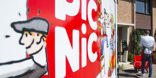Supermarktdeskundigen zijn sceptisch over de kansen van online boodschappenbezorger Picnic. Toch lijkt de startup niet kansloos, zegt Retailwatching.nl. Of Jumbo en Ahold zich op dit moment achter de oren krabben, valt nog te bezien. Picnic is de zoveelste speler die een gooi doet naar een rendabel verdienmodel in de online boodschappenmarkt. De koek in het online segment is nog altijd klein. De webwinkels waren vorig jaar goed voor anderhalf procent van de supermarktomzet. De oorzaken van de geringe online omzet zijn voor de hand liggend. De supermarktdichtheid in ons land is hoog, waardoor consumenten gemiddeld binnen tien minuten bij een supermarkt zijn. De factoren gemak en tijdswinst wegen voor online boodschappen dus minder zwaar dan voor de aanschaf van een paar schoenen. Bovendien worstelen supermarkten met de logistiek die e-commerce met zich mee brengt. Versproducten kunnen moeilijk een week in een distributiecentrum blijven liggen en al helemaal niet een dag in de volle zon bij de voordeur van de klant staan. En de pick-up points mogen dan als paddenstoelen uit de grond schieten, tachtig procent van de Nederlanders wil thuisbezorging, zo berekende dataleverancier Syndy onlangs. Picnic kent deze factoren en denkt het antwoord te hebben. Online boodschappen doen is volgens de etailer nog niet doorgebroken in ons land, omdat consumenten hoge bezorgkosten moeten betalen. Picnic bezorgt daarom gratis en biedt een laagste prijsgarantie. Dat zal al veel geldbewuste Hollanders over de streep trekken. Hoe rekent Picnic zijn verdienmodel rond? Drie redenen waarom deze nieuwkomer het misschien wel redt en reuzen als Ahold en Jumbo kan kietelen. 1. Innovatieve logistiek Picnic heeft ‘in stilte drie jaar lang met een team van dertig specialisten’ gewerkt aan een nieuwe distributiemethode, zo laat de websuper weten. In een aantal Amersfoortse wijken vindt momenteel een pilot plaats waarbij consumenten hun aankopen laten afleveren. Daarbij zijn zoveel mogelijk tussenschakels geëlimineerd. Vanuit een distributiecentrum in Nijkerk wordt een hub in Amersfoort bevoorraad. De bezorging gebeurt met elektrische busjes die de testers naar eigen zeggen doen denken aan een moderne SRV-wagen. De speciaal ontwikkelde voertuigen zijn verbonden met internet. Klanten bestellen en betalen via de app, kiezen welke rit het beste in hun schema past en weten tot op dertig minuten nauwkeurig hoe laat hun boodschappen worden bezorgd. De kosten van deze manier van distributie zijn volgens Picnic laag genoeg om de bezorging gratis te kunnen houden èn een laagste prijsgarantie te kunnen bieden. 2. Lage kosten In tegenstelling tot fysieke supermarkten die een webwinkel lanceren heeft Picnic geen dure panden. Picnic kampt ook niet met weerspannige franchisers die een percentage willen van de online bestellingen uit hun postcodegebied. Picnic hoeft bovendien geen grote voorraden aan te houden, omdat de webwinkel alleen inkoopt wat er is besteld door klanten. Voor de inkoop werkt de websuper samen met Boni. Handig, omdat Boni als Superunie-lid vrij gunstige inkoopprijzen kan bedingen. Marketingexpert Paul Moers plaatst daar overigens wel gelijk een kanttekening bij. "Boni is een van kleinste partijen en tegen de 'inkooppower' van Albert Heijn kun je simpelweg niet op", stelt hij tegen NOS. Over het concept is hij kort en bondig: "Een krankzinnig idee." Supermarktkenner Gerard Rutte is optimistischer. “Ik verwacht dat ze de markt een beetje op z'n kop gaan zetten. Ook slim dat ze niet bezorgen in vieze autootjes, maar in elektrische. Ze gokken op de massa en niet op een paar bezorgingen." 3. De knappe koppen achter Picnic De vier compagnons van de aanstormende websuper zijn niet de eerste de beste. Michiel Muller bijvoorbeeld richtte in 2004 ANWB-uitdager Route Mobiel op. Het een gevestigde partij moeilijk maken is iets waar hij zijn hand dus niet voor omdraait. Datzelfde geldt voor investeren in een concept dat zich nog moet bewijzen. “Dit is een kapitaalintensief traject, dus je moet bereid zijn om serieus te investeren”, vertelt hij aan Sprout. “Je kunt je voorstellen dat je met een team van dertig mensen niet uitkomt met vijftigduizend euro.” De andere drie compagnons deden al ervaring op in de retail. Internetondernemers Joris Beckers en Frederik Nieuwenhuys waren eerder eigenaar van Fredhopper, dat personalisatiesoftware voor webwinkels ontwikkelde om voor meer conversie te zorgen. Een greep uit de klantenkring: de Bijenkorf, Waitrose, Otto en Albert Heijn. Bij laatstgenoemde werkte ook Bas Verheijen, initiatiefnemer nummer vier. Tussen 2008 en 2012 was hij marketingdirecteur bij C1000. Gezamenlijk vormen de vier compagnons een interessant team, met een aantal belangrijke eigenschappen. Het lef om relatief onontgonnen terrein te betreden, de technologische knowhow om van bezoekers shoppers te maken, kennis van de foodmarkt en manieren om producten aan de man te brengen: het komen allemaal samen binnen Picnic. Eerdere pogingen van onder meer Superdirect.com en Truus.nl liepen op niets uit. Nou ja, op faillissementen dan. Vanaf komende maand kunnen we zien of Picnic zijn beloften inlost, of eveneens zijn tanden stuk bijt op de online boodschappenmarkt. Lees ook op Retailwatching.nl Dit maakt China Koning Namaak 'Goede' hamburger rukt op in Amerika Het prijzencircus in winkels is dood; leve de loyaliteit