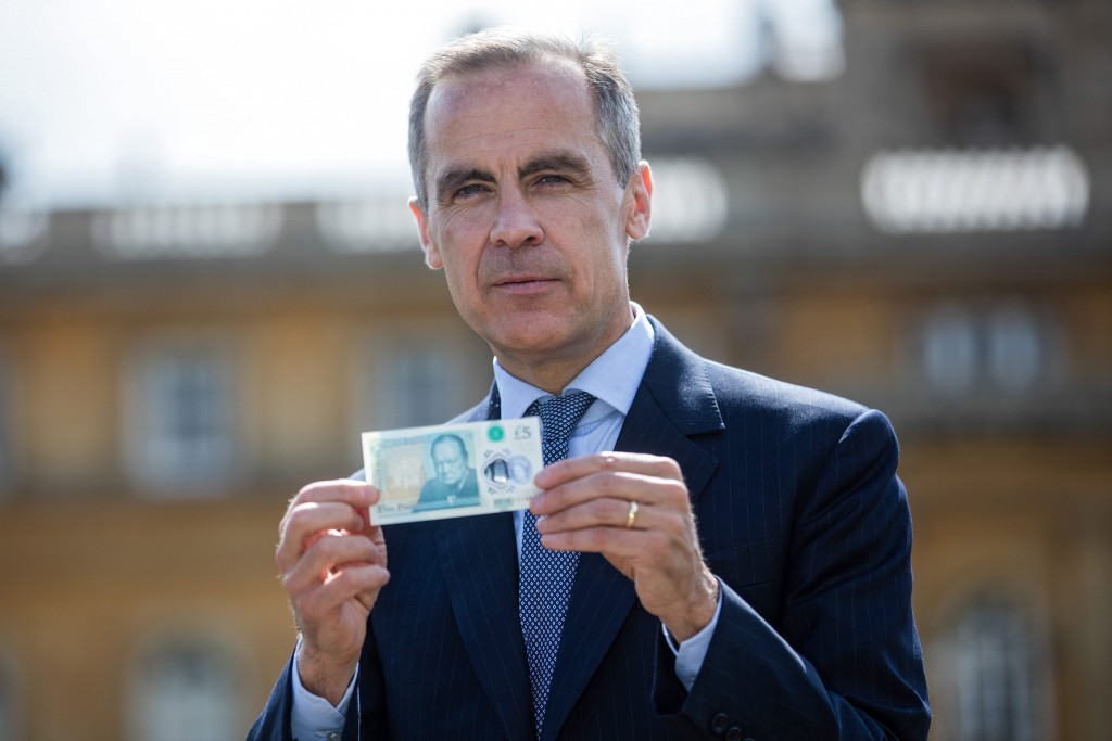 Mark Carney, topman van The Bank of England, toont het nieuwste biljet van vijf pond, met Winston Churchill. Foto: EPA