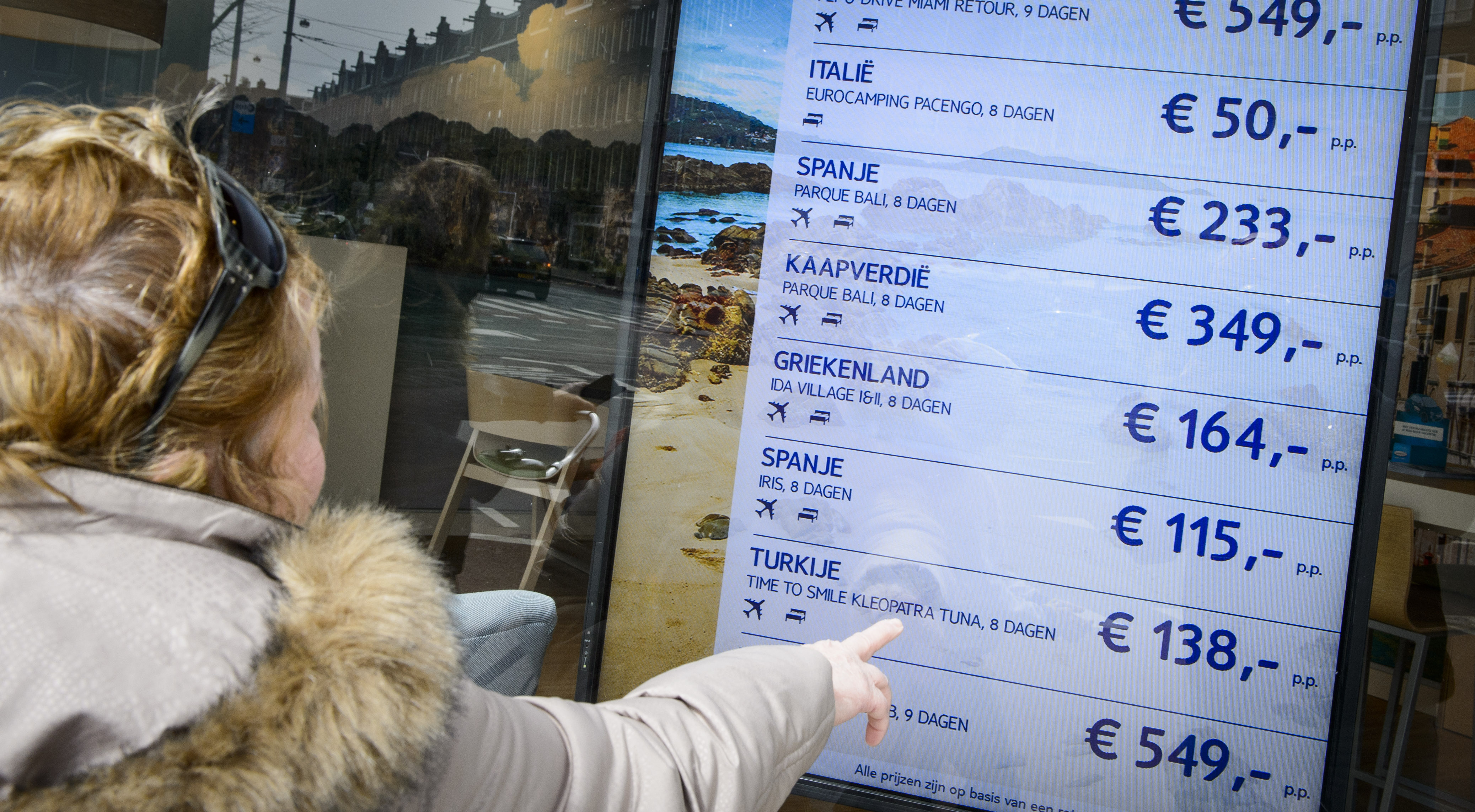 2016-04-29 15:45:41 AMSTERDAM - Een vrouw bekijkt de vakantie aanbiedingen, voor een vakantie naar de zon, bij reisorganisatie TUI. ANP LEX VAN LIESHOUT