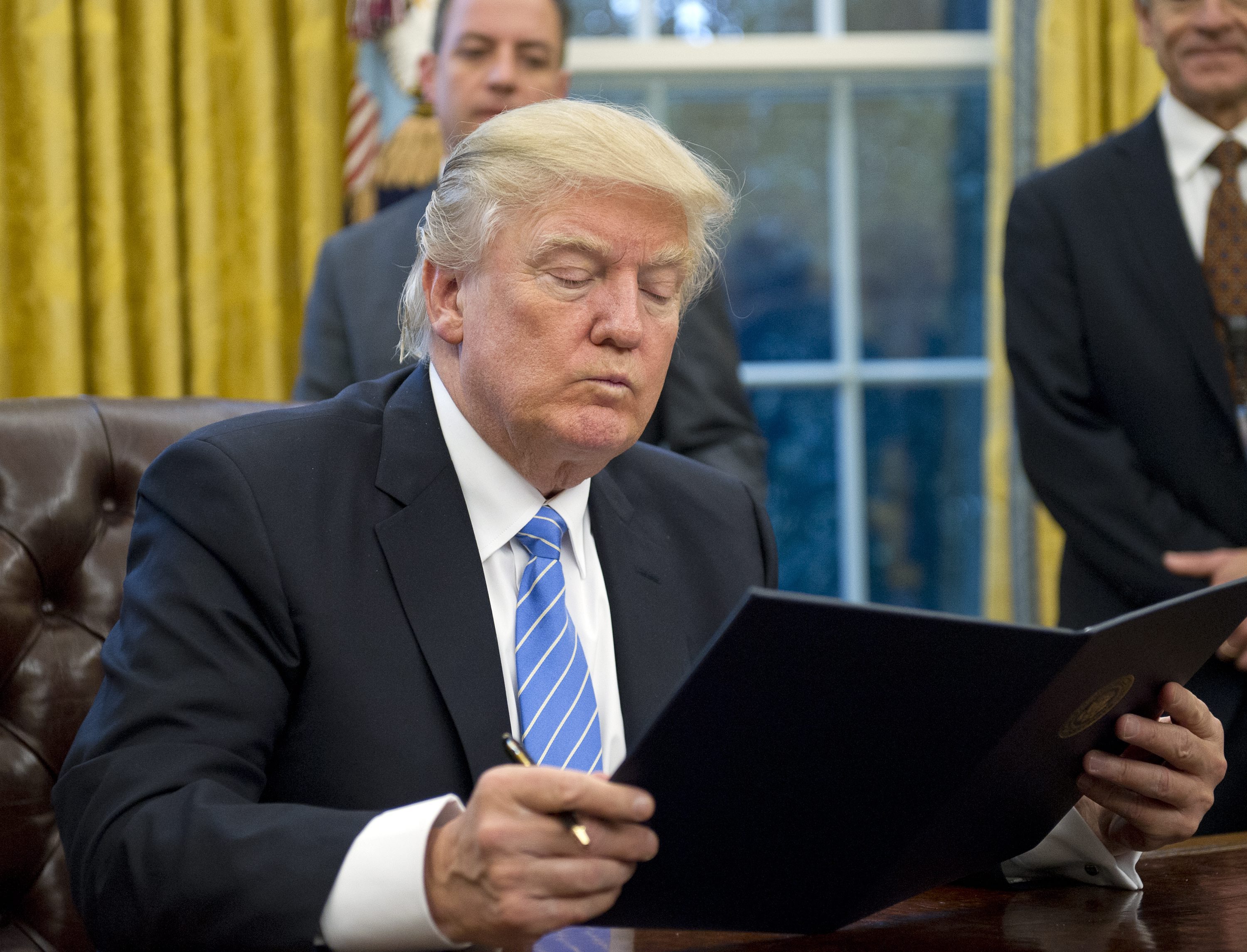 2017-01-23 11:46:33 epa05744780 US President Donald J. Trump reads the first of three Executive Orders he will sign in the Oval Office of the White House in Washington, DC, USA, 23 January 2017. They concerned the withdrawal of the United States from the Trans-Pacific Partnership (TPP), a US Government hiring freeze for all departments but the military, and "Mexico City" which bans federal funding of abortions overseas. EPA/Ron Sachs / POOL