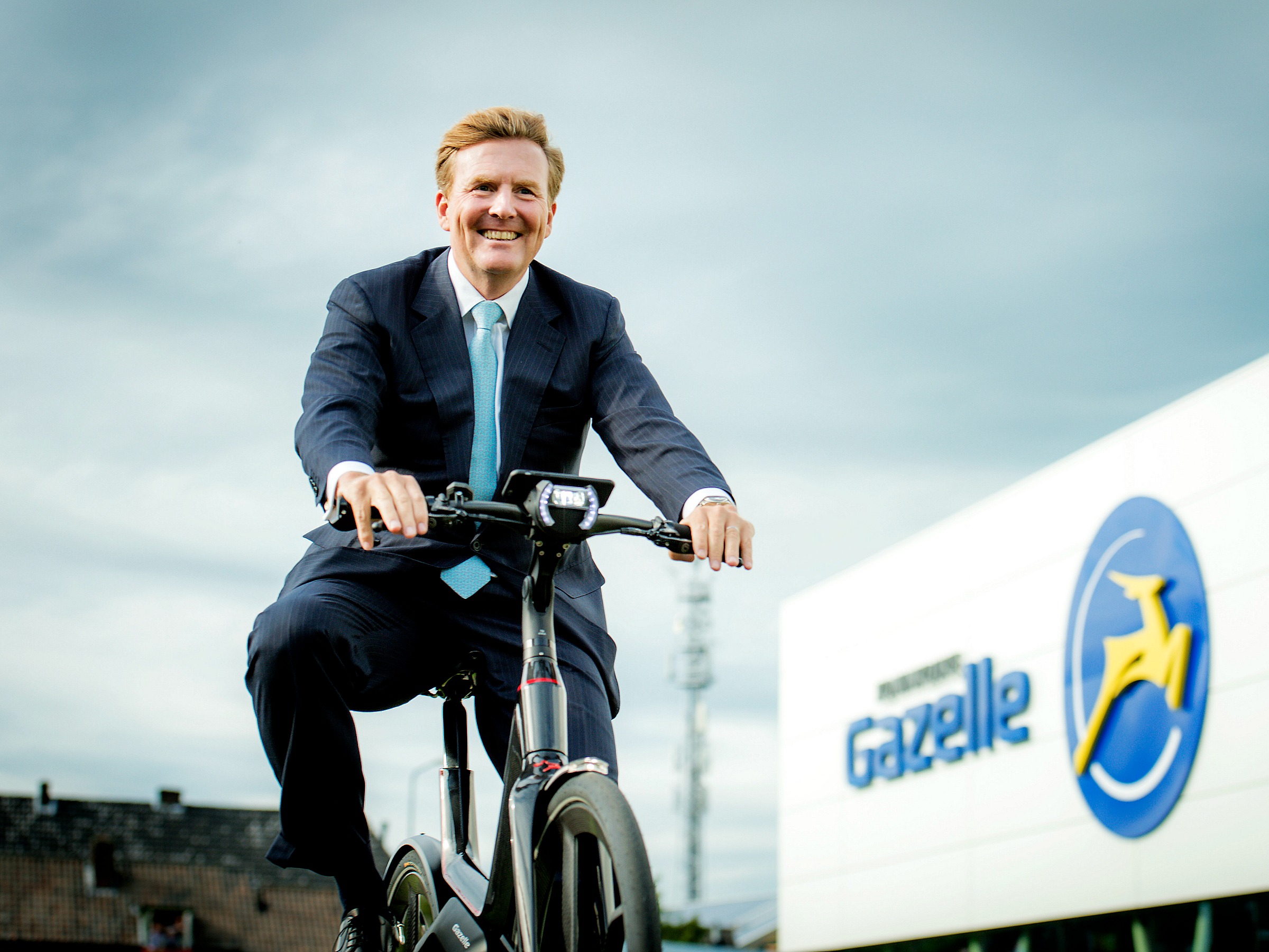 Koning Willem-Alexander fietst tijdens de opening van de nieuwe fabriek van Gazelle in 2015 een rondje op een e-bike.