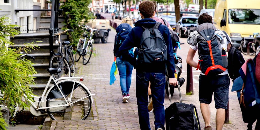 Toeristen met rolkoffers op de grachten in Amsterdam. Rolkoffers zijn een van de problemen van toenemende populariteit van Airbnb.