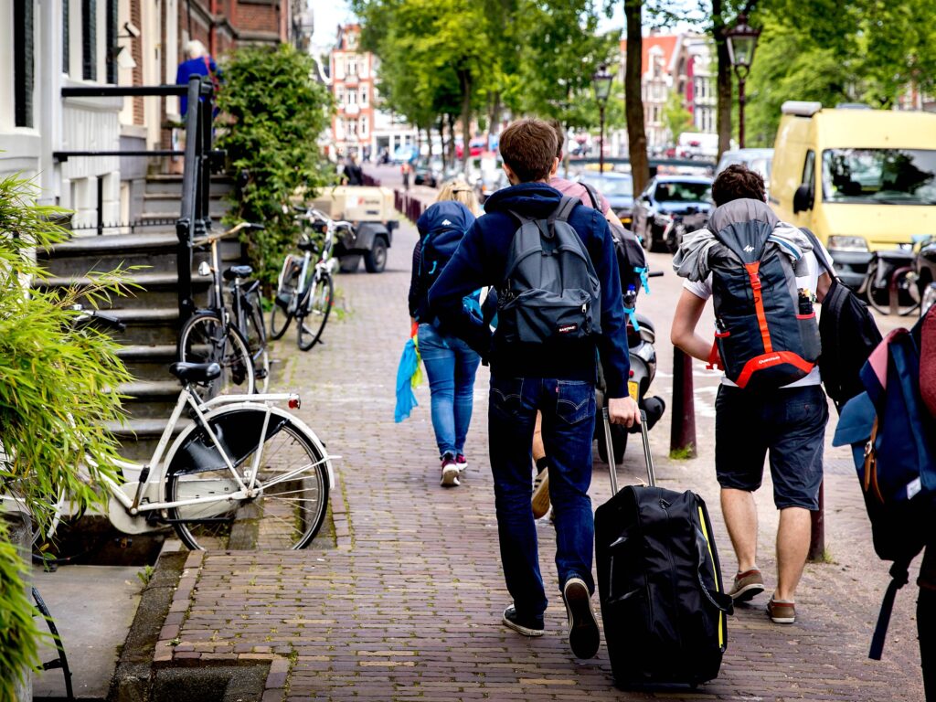 Toeristen met rolkoffers op de grachten in Amsterdam. Rolkoffers zijn een van de problemen van toenemende populariteit van Airbnb.