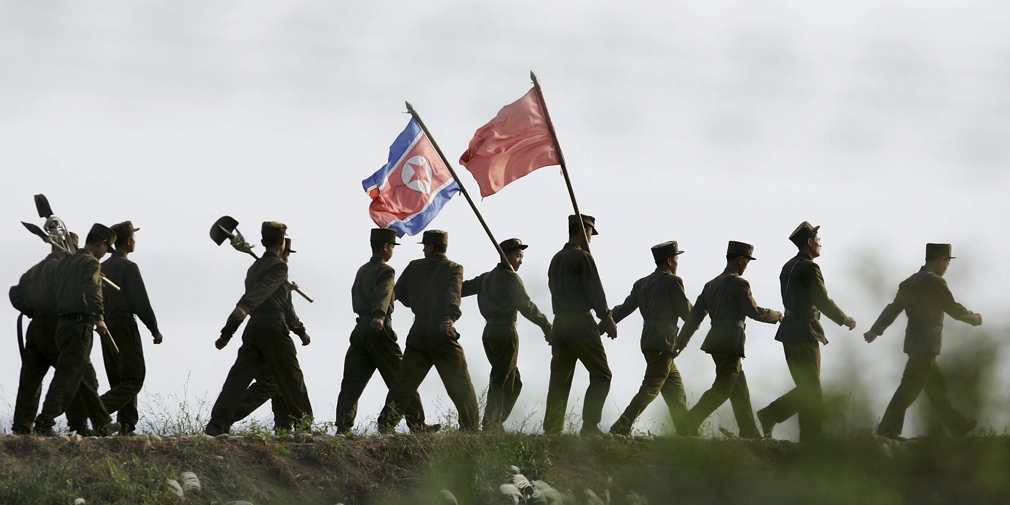 North Korean soldiers carrying the North Korean flag and shovels march after working at the farmland on the outskirts of the North Korean city of Sinuiju in this picture taken on October 18, 2006 in the Chinese border city of Dandong, Liaoning Province of China. North Korean soldiers carrying the North Korean flag and shovels march after working at the farmland on the outskirts of the North Korean city of Sinuiju in this picture taken on October 18, 2006 in the Chinese border city of Dandong, Liaoning Province of China.