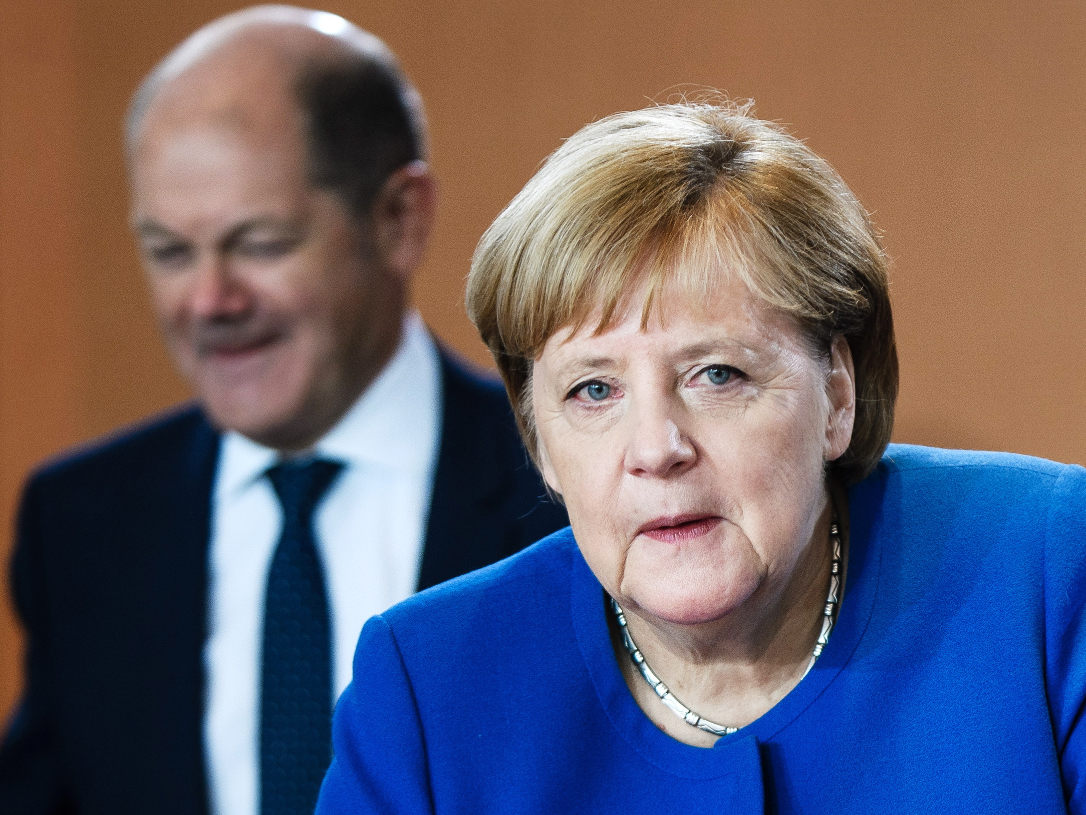 De Duitse bondskanselier Angela Merkel met op de achtergrond de Duitse minister van Financiën Olaf Scholz.