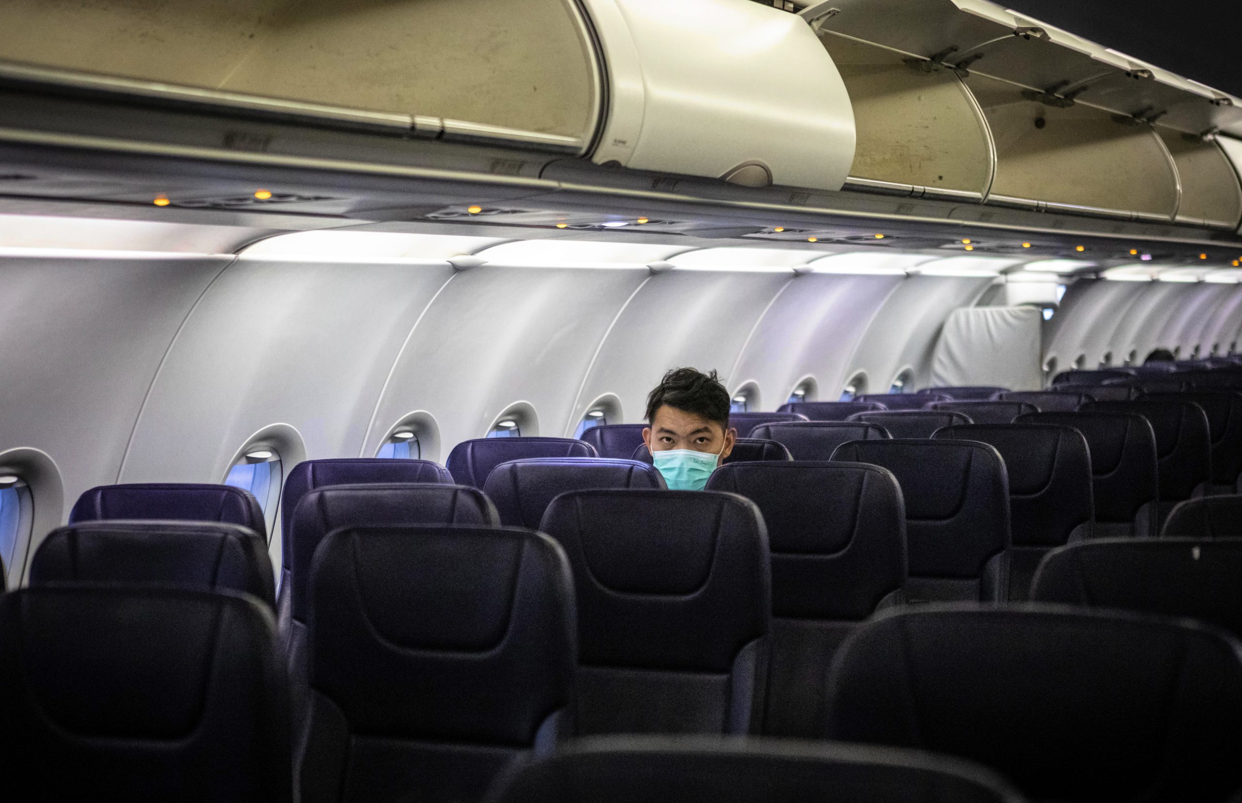 Een man met een mondkapje in een vliegtuig