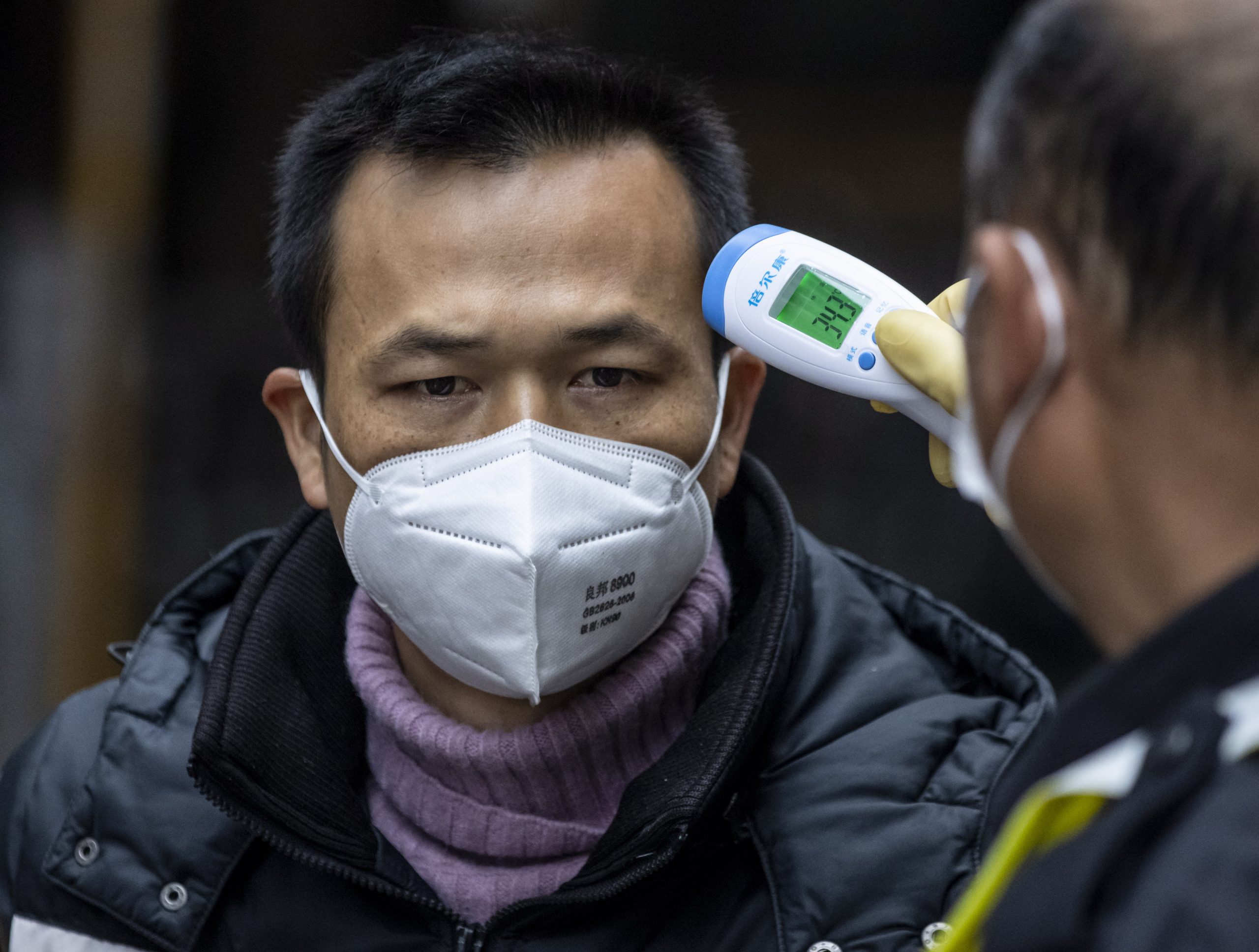 Bij bezoekers van een vismarkt in Guangzhou wordt de temperatuur gemeten.