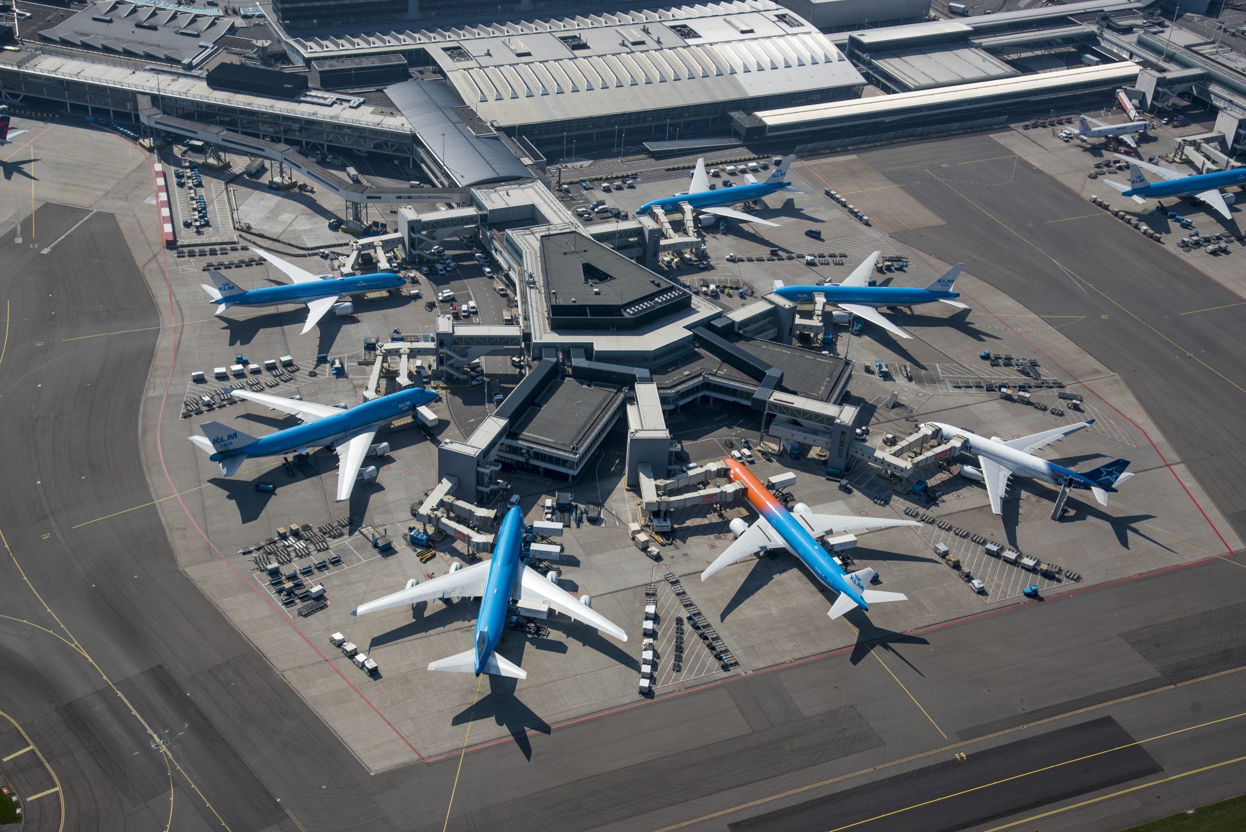 Luchtfoto van Schiphol, met vliegtuigen aan de gate bij de F-pier.