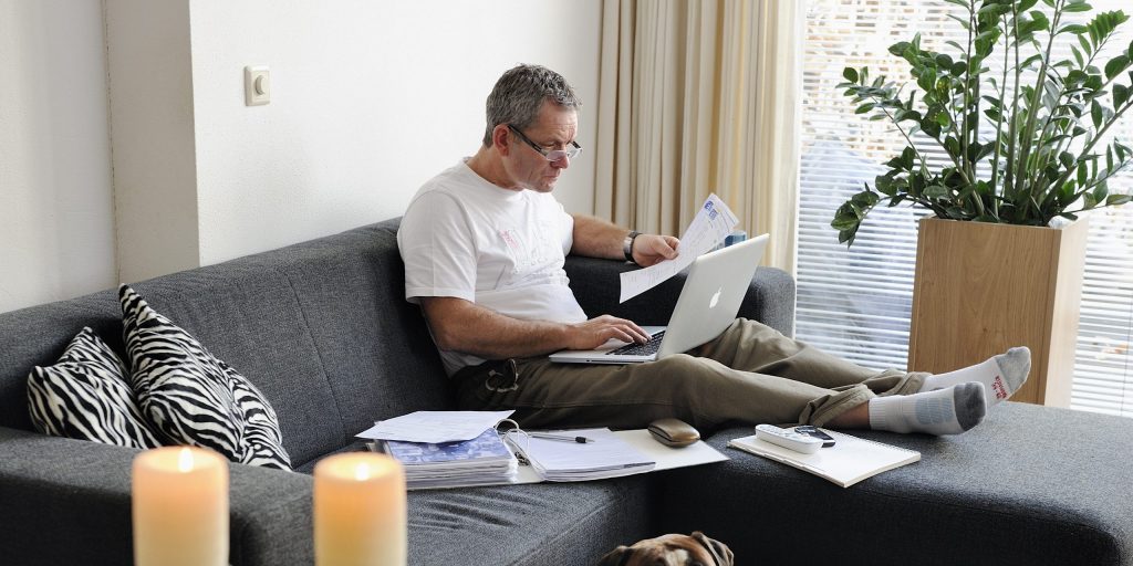 Een man werkt huis op de bank