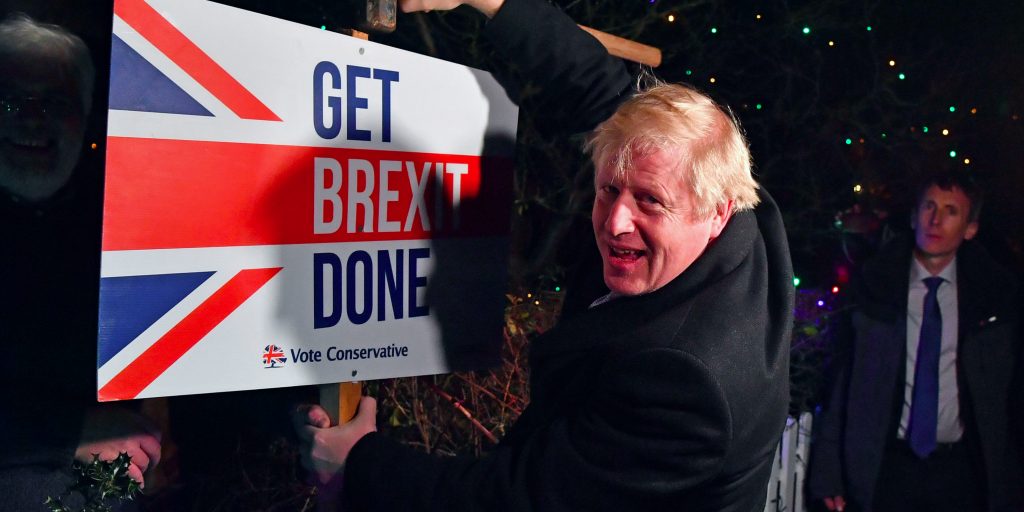 De Britse premier Boris Johnson timmert een bord met 'Get Brexit Done' in de grond