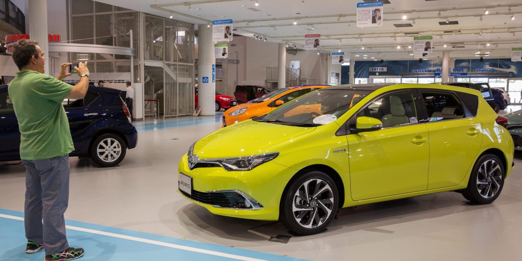 Een man neemt een foto van een Toyota in een showroom