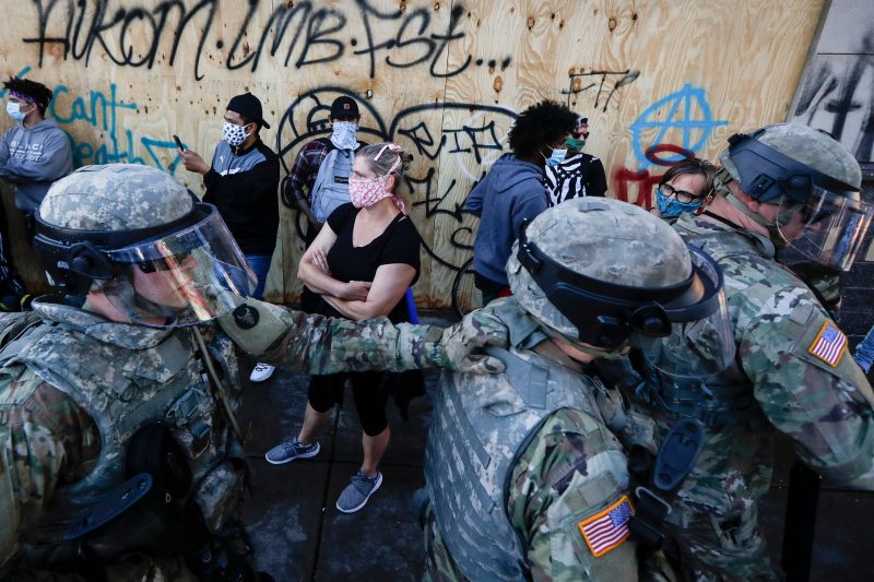National Guard personnel return to their defensive position as protesters make room for them to fall back following a confrontation on East Lake Street, Friday, May 29, 2020, in St. Paul, Minn