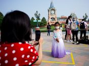 Een vrouw neemt een foto van haar dochter met mondkapje in Shanghai Disneyland