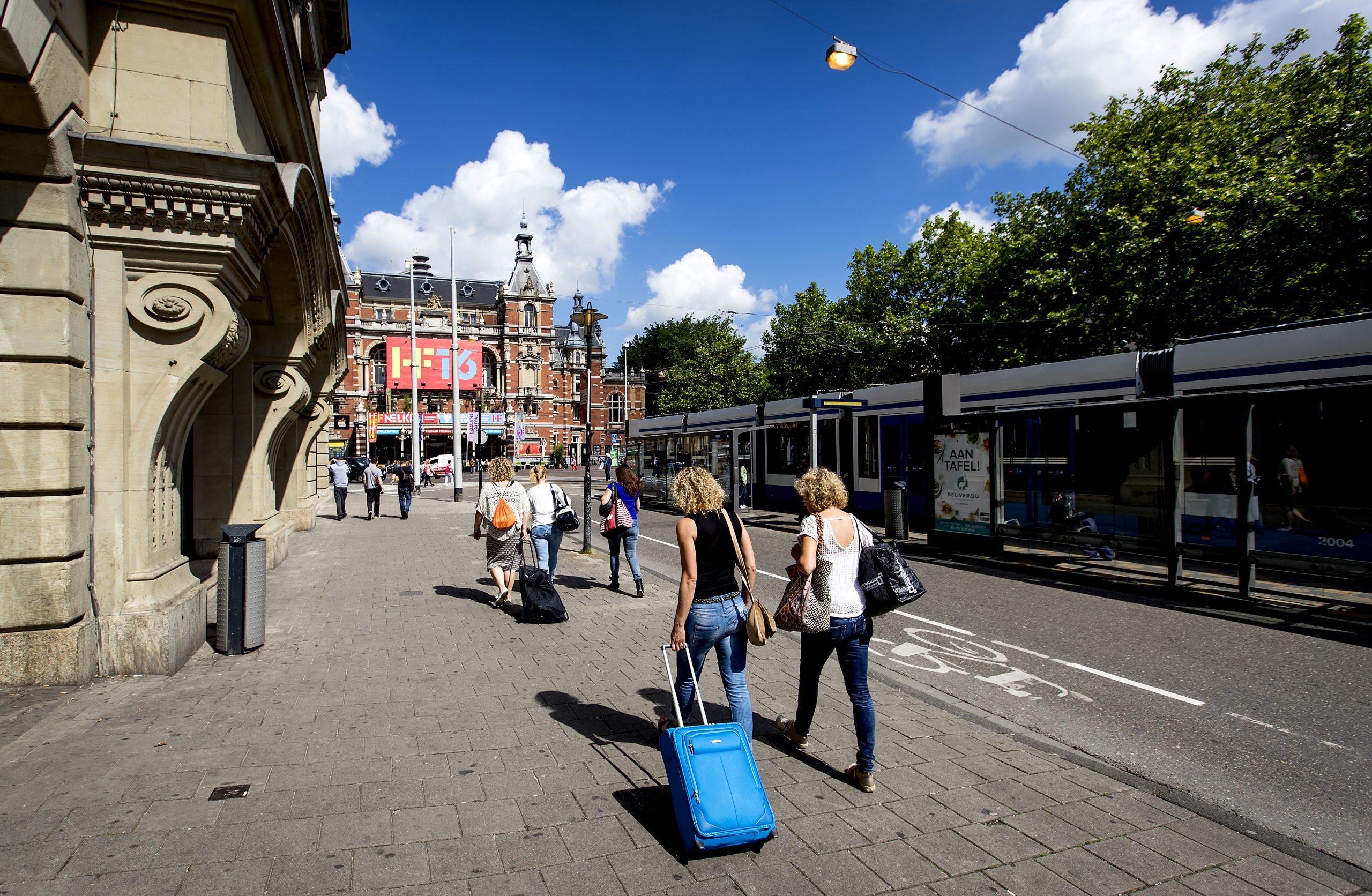 Toeristen met rolkoffer op het Leidseplein in Amsterdam.