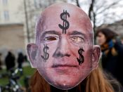 Een demonstrant met een masker van Amazon-topman Jeff Bezos