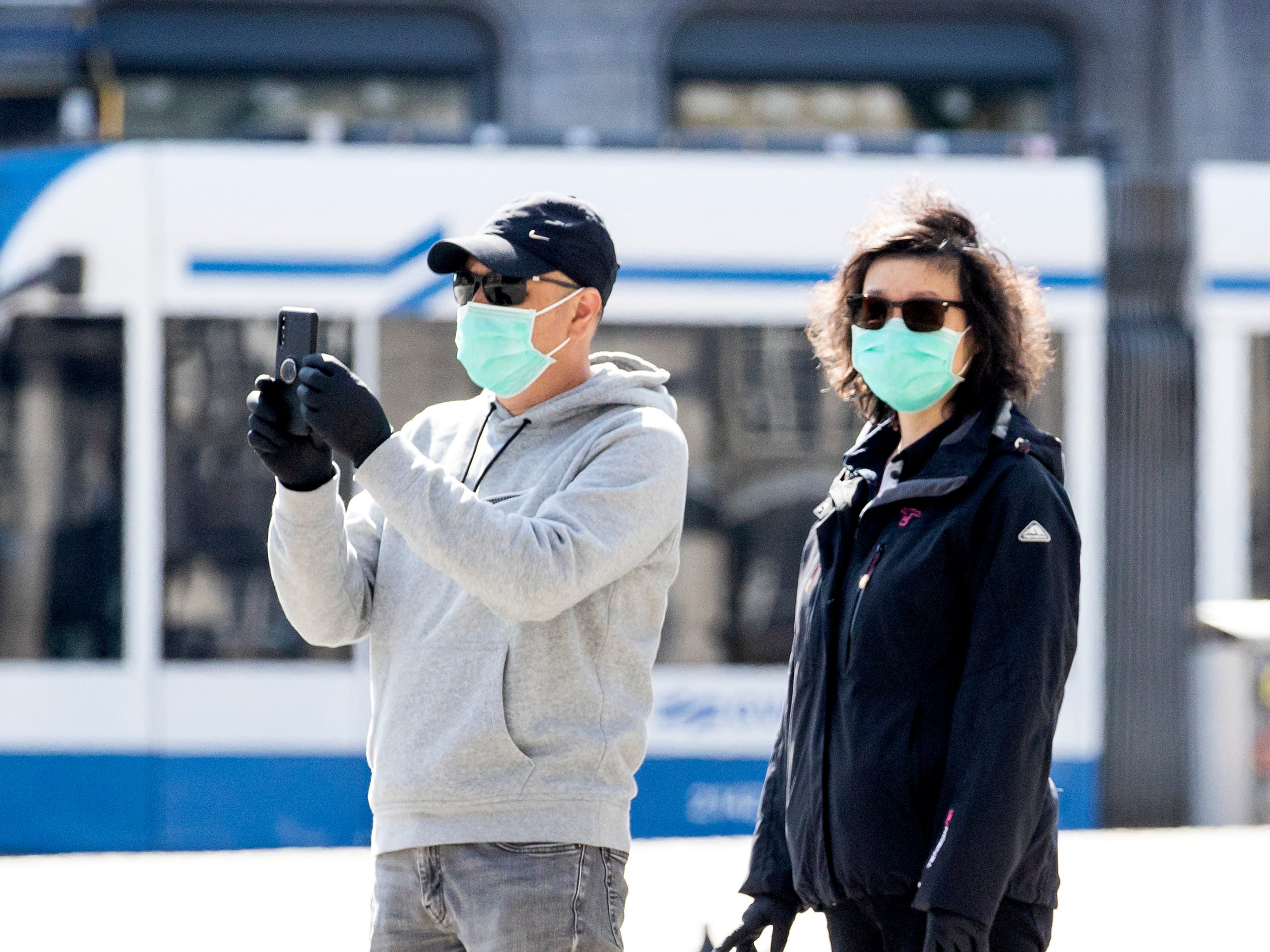 Een man en vrouw dragen een mondkapje op straat.