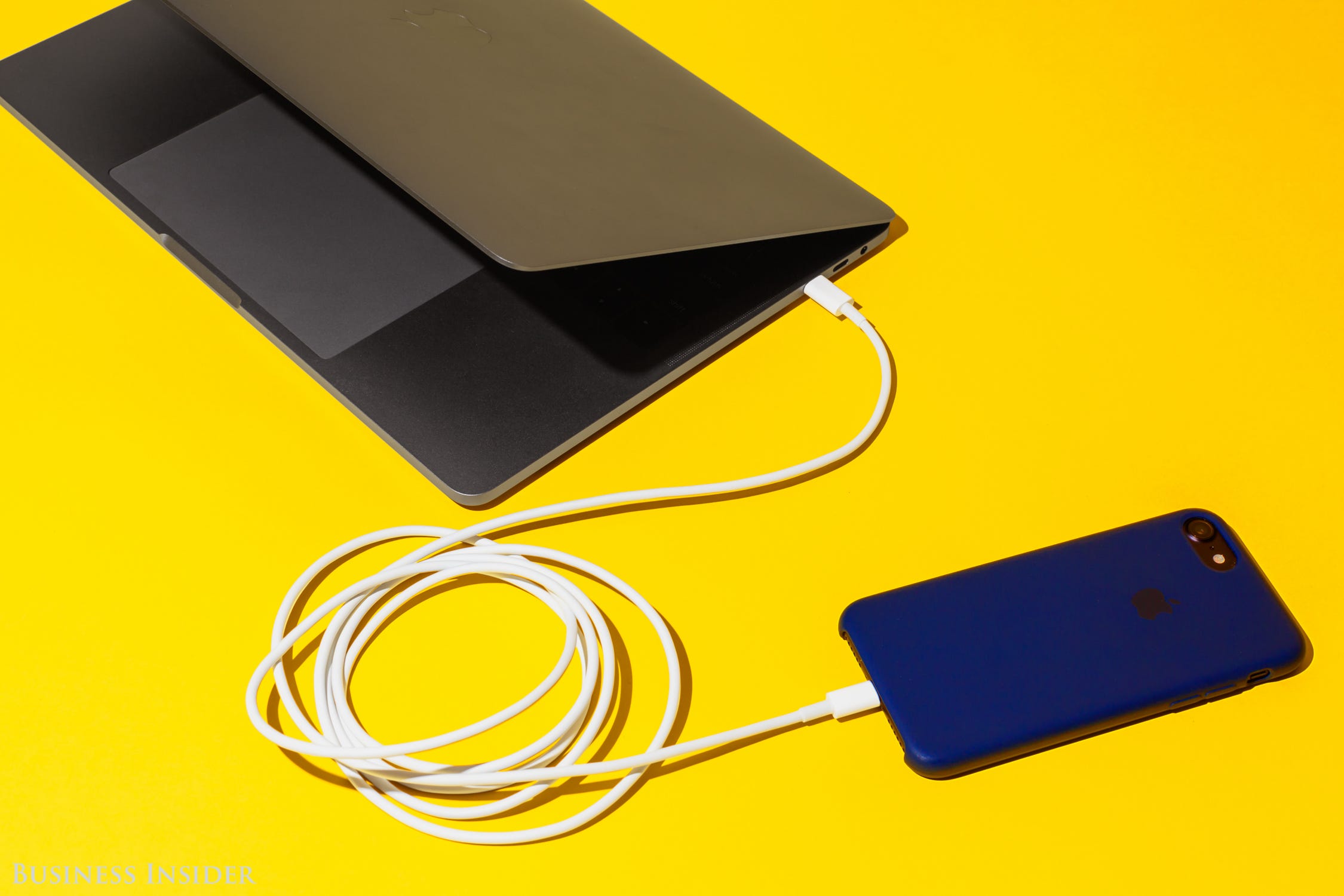 USB-C op een Macbook verbonden aan een lightningconnector op de iPhone. Foto: Hollis Johnson/Business Insider
