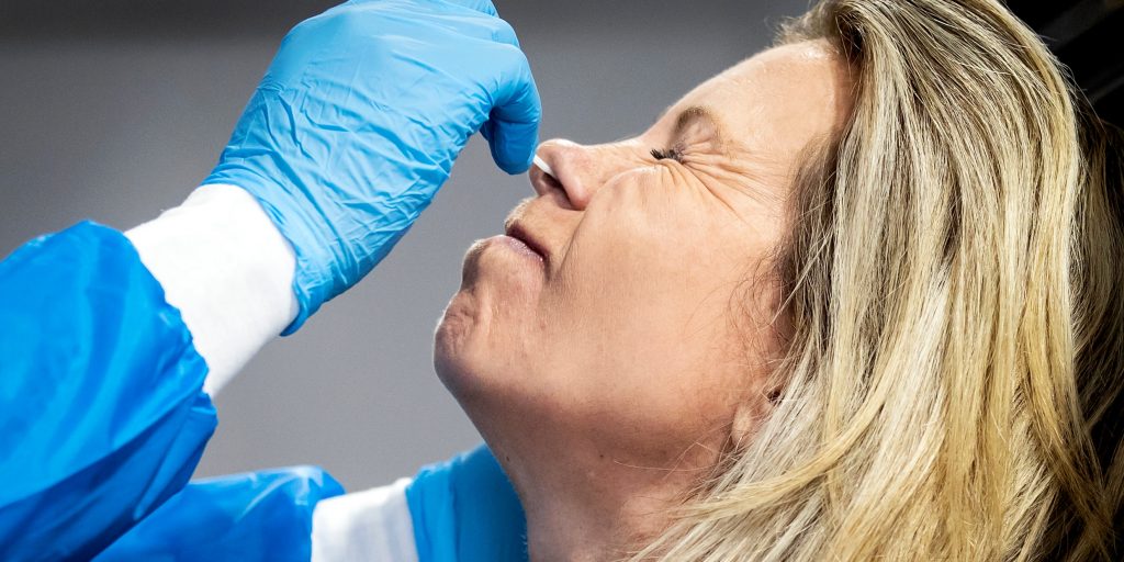 Een medewerker van de GGD Rotterdam-Rijnmond neemt een coronatest af in een teststraat.