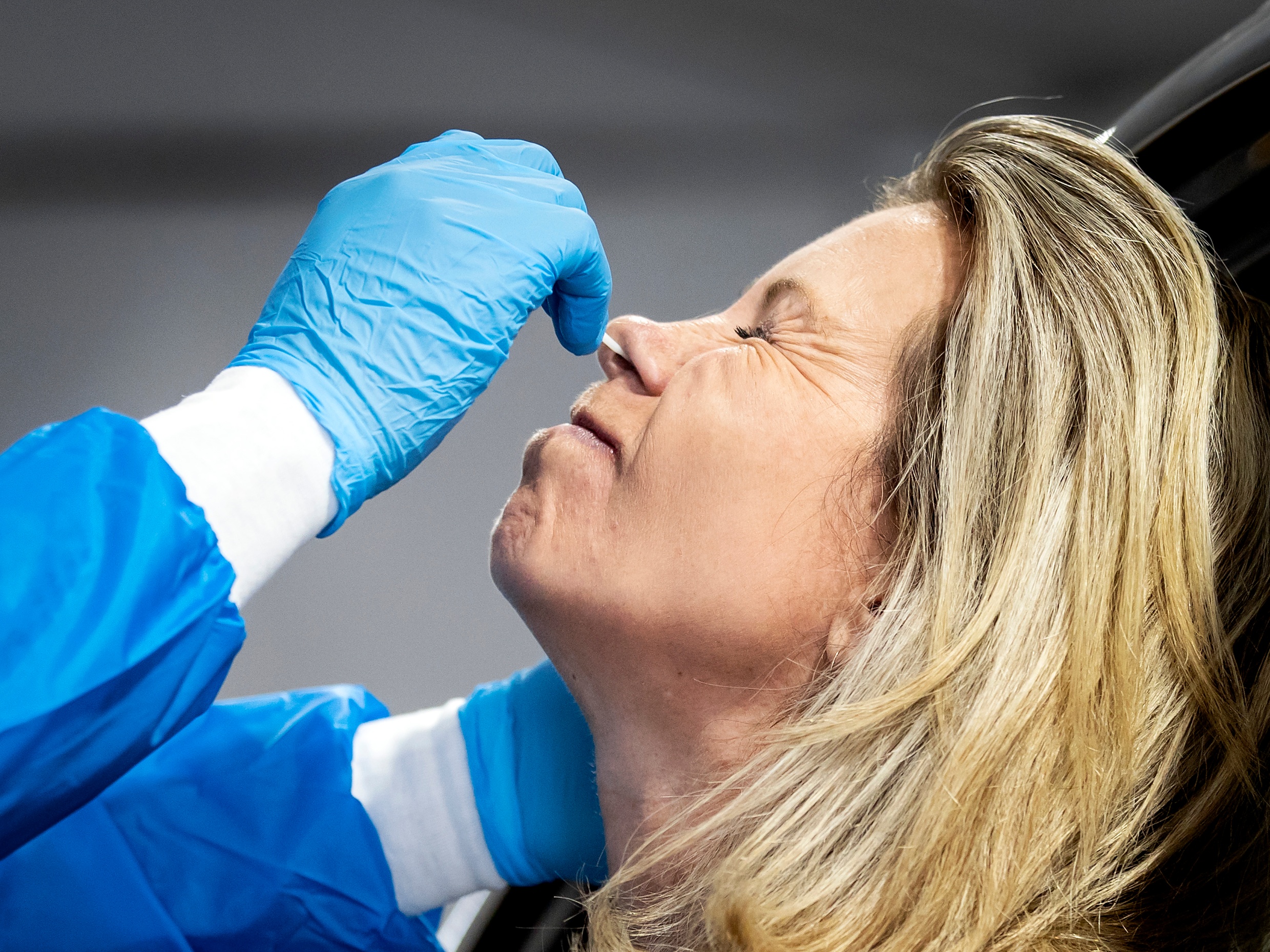 Een medewerker van de GGD Rotterdam-Rijnmond neemt een coronatest af in een teststraat.