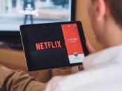 Een man kijkt Netflix op zijn tablet thuis op de bank