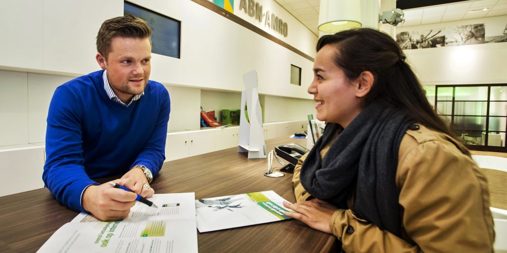 Een medewerker van ABN AMRO (L) bij een filiaal van ABN AMRO in Amsterdam.