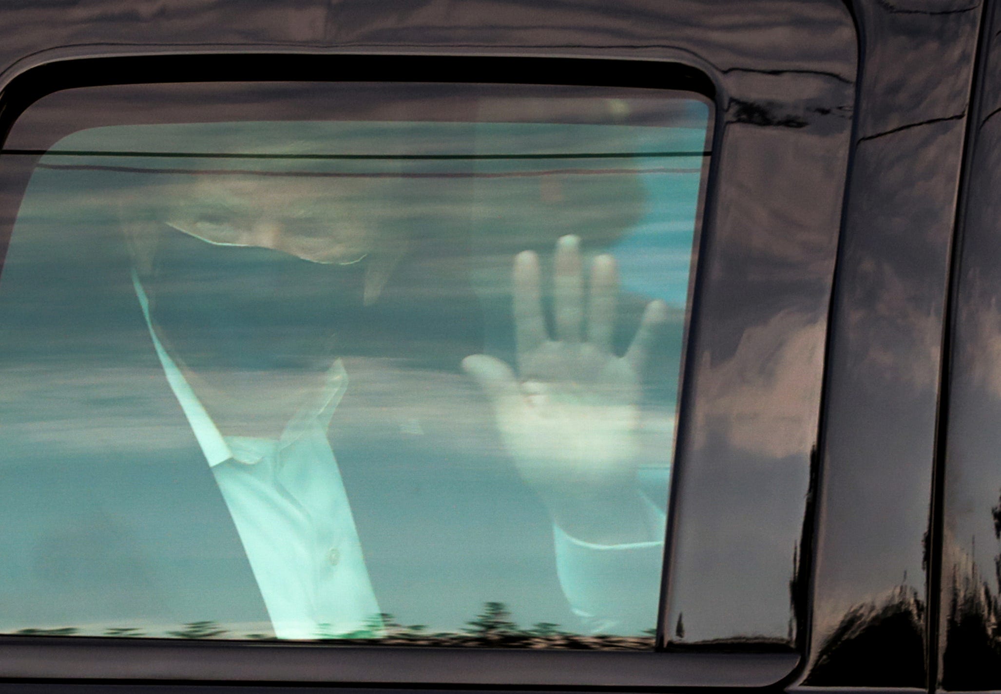 President Donald Trump zwaait naar aanhangers vanuit zijn auto voor het Walter Reed National Military Medical Center. Hij werd hier behandeld na zijn besmetting met het coronavirus. Foto: Cheriss May/Reuters