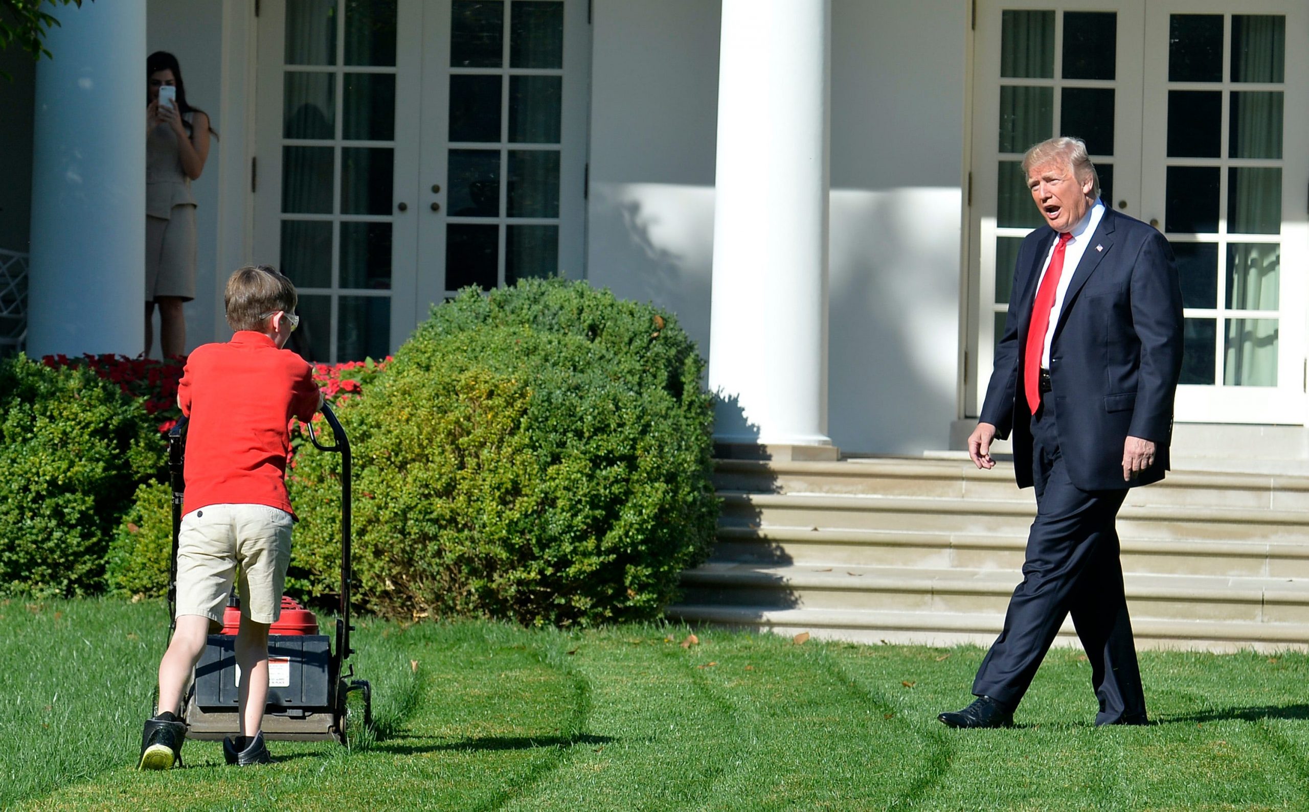President Donald Trump verheft zijn stem terwijl de 11-jarige Frank Giaccio het gazon van het Witte Huis maait. Foto: Mike Theiler/AFP via Getty Images