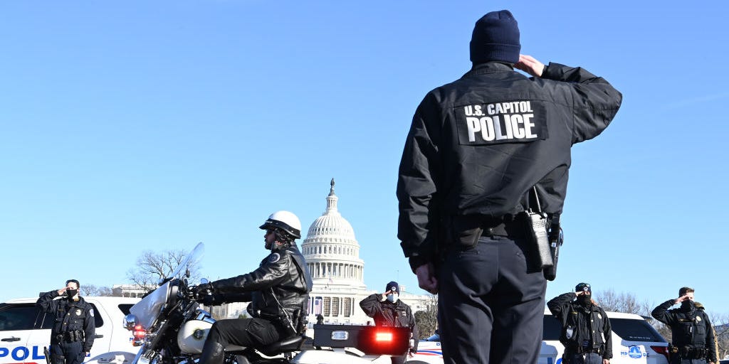 Police officers salute during the procession for U.S. Capitol police officer, Brian D. Sicknick as they stand along Third Street SW on Sunday January 10, 2021 in Washington, DC.
