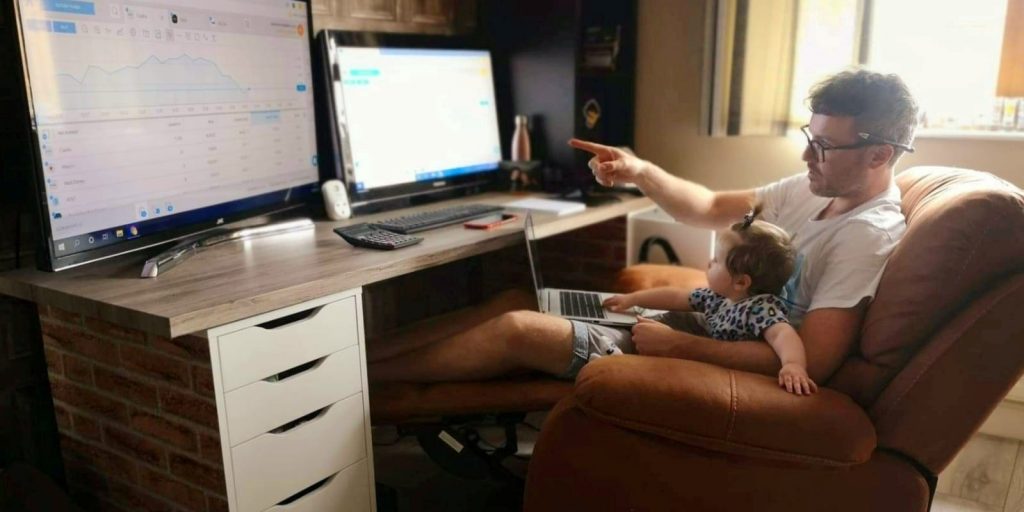 Daytrader Damian McVeigh sits in front of computers with his daughter Avril at home during the coronavirus disease (COVID-19) outbreak, in Belfast, Northern Ireland June 16, 2020.
