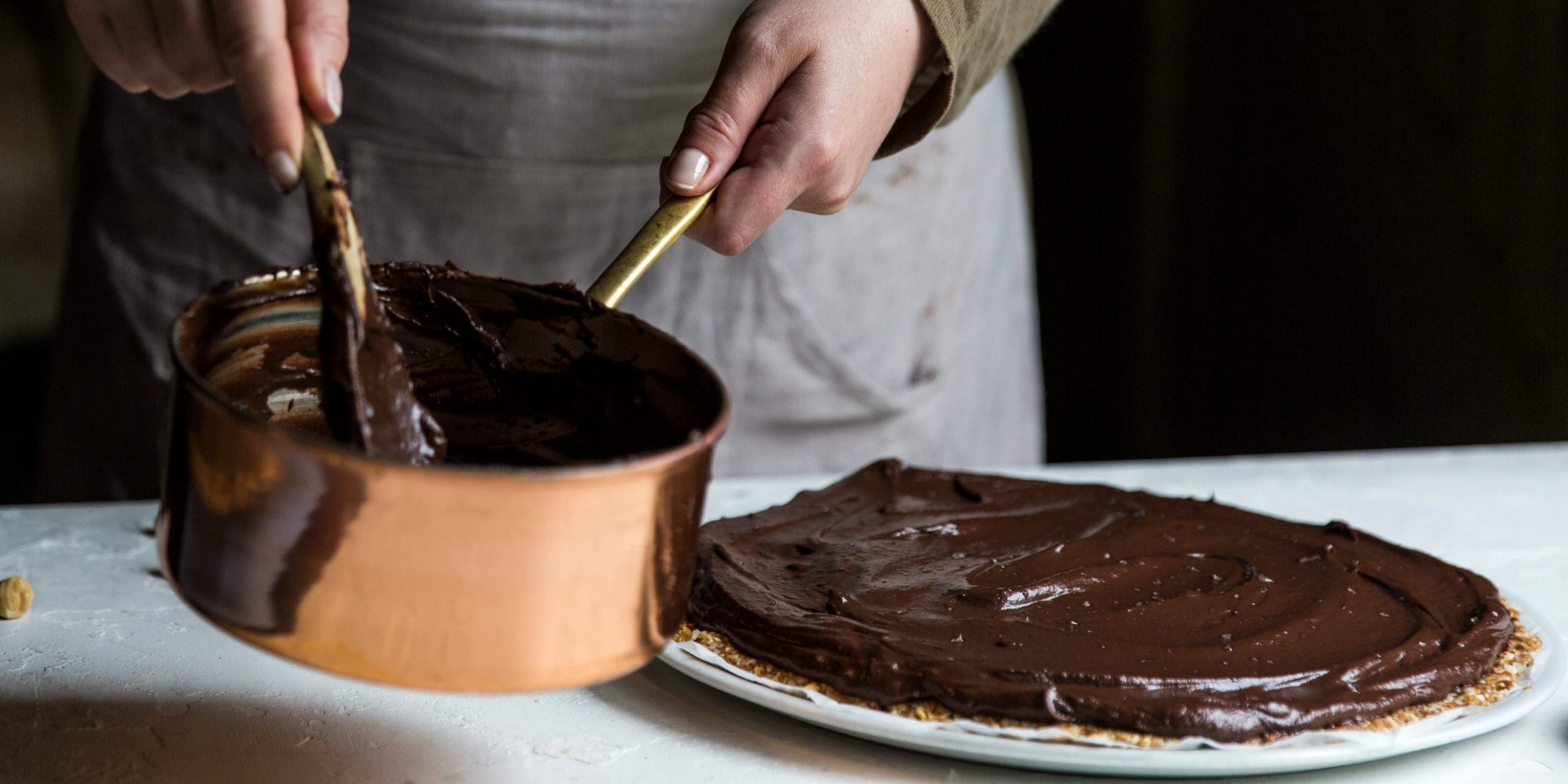 person spreading chocolate from copper pot