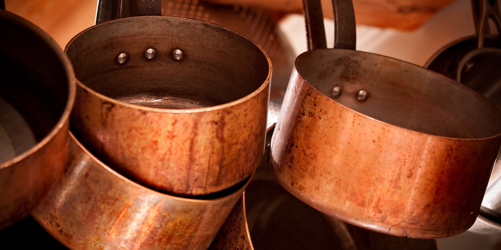 aged copper cookware hanging on rack