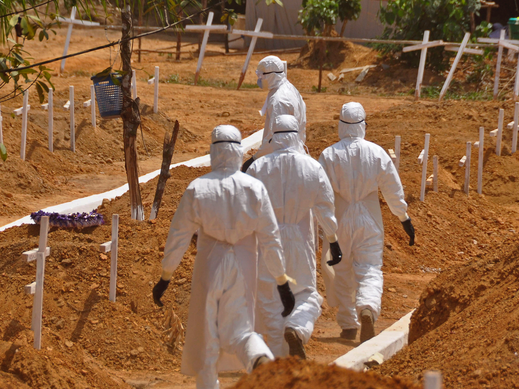 health workers walk inside a new graveyard for Ebola victims, on the outskirts of Monrovia, Liberia. Despite the drop in reported Ebola cases, Dr. Bruce Aylward, leading WHO’s Ebola response, declared Friday April 10, 2015, that it’s too early for World Health Organization to downgrade the global emergency status of the biggest-ever Ebola outbreak in Africa.