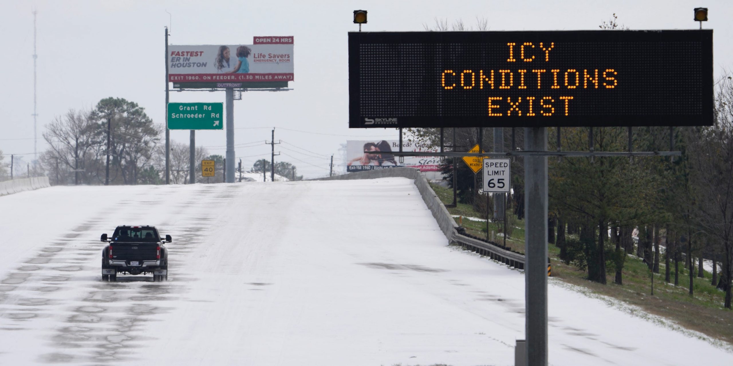 A truck drives past a highway sign Monday, Feb. 15, 2021, in Houston. A frigid blast of winter weather across the U.S. plunged Texas into an unusually icy emergency Monday that knocked out power to more than 2 million people and shut down grocery stores and dangerously snowy roads.