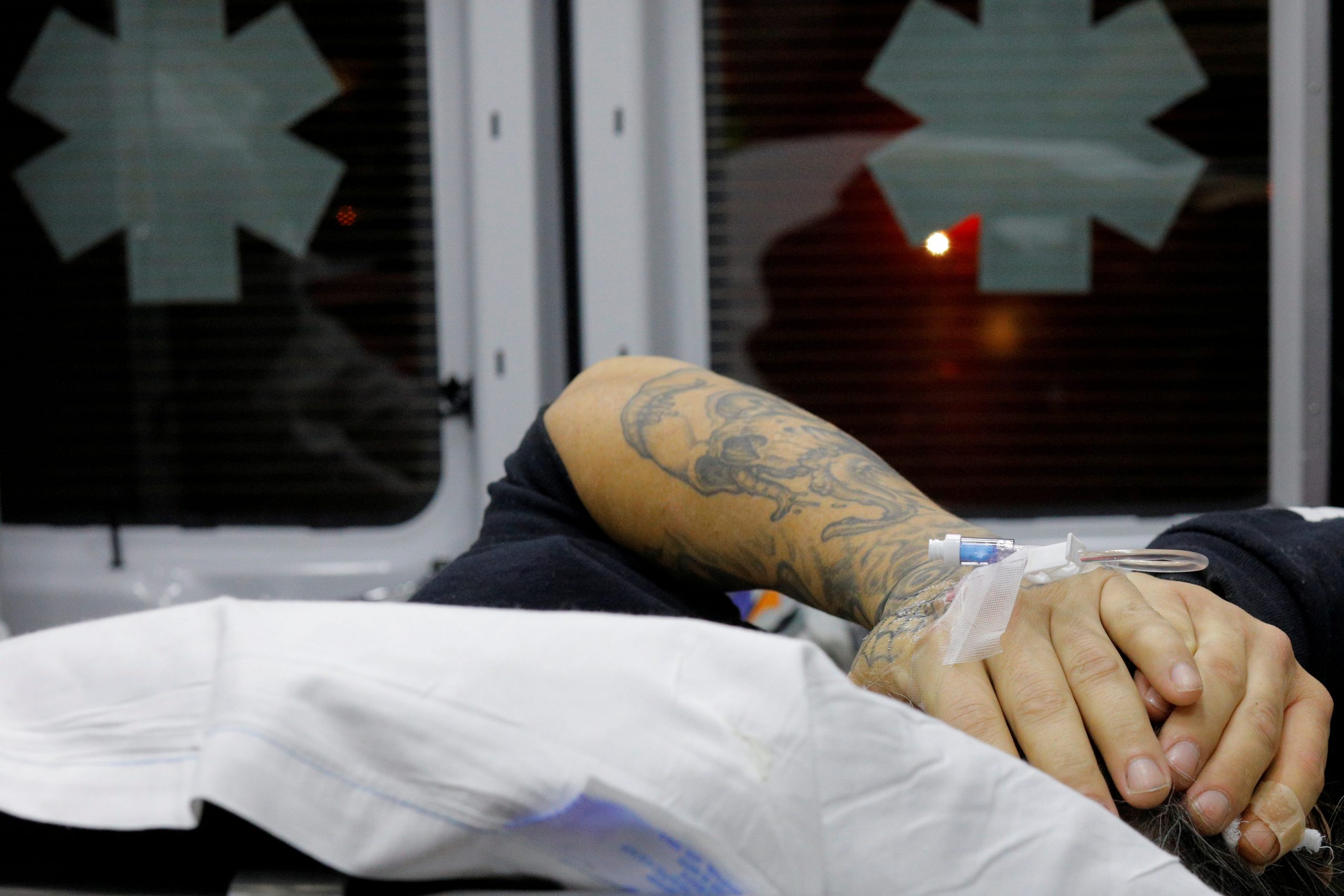 FILE PHOTO: A 41-year-old man found unconscious after overdosing on opioids in the driver's seat of a car, with the engine running and the transmission in drive, puts his hands over his head in the back of a Cataldo Ambulance at a gas station in the Boston suburb of Malden, Massachusetts, December 2, 2017. REUTERS/Brian Snyder/File Photo