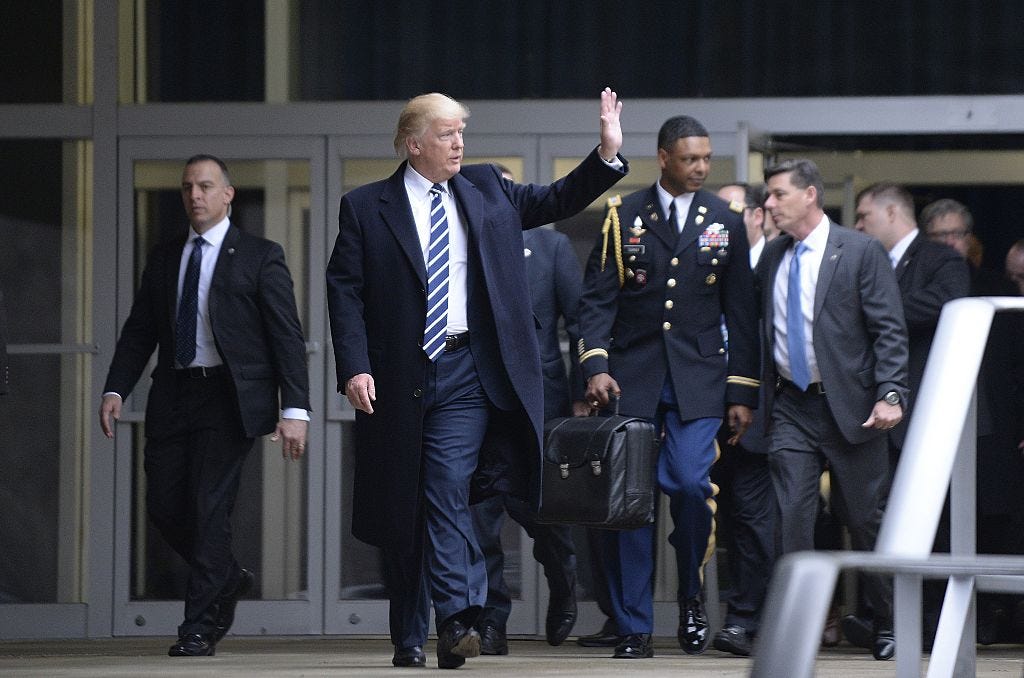 US President Donald Trump leaves the CIA headquarters after speaking to 300 people on January 21, 2017 in Langley, Virginia . Trump spoke with about 300 people in his first official visit with a government agency. In the background a military aid carries the 'football.'