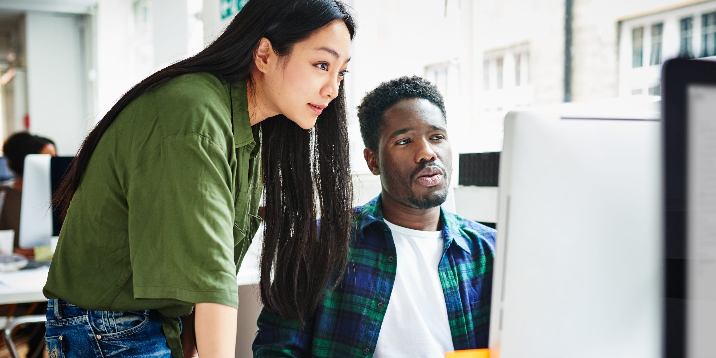 coworkers looking at desktop computer at work