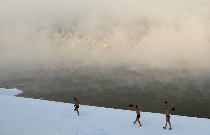 Enthusiasts of winter swimming warm up on the bank of the Yenisei River ahead of their weekly bathing session, with the air temperature at about minus 30 degrees Celsius (minus 22 degrees Fahrenheit), in the Siberian town of Divnogorsk, Russia November 18, 2016. REUTERS/Ilya Naymushin 