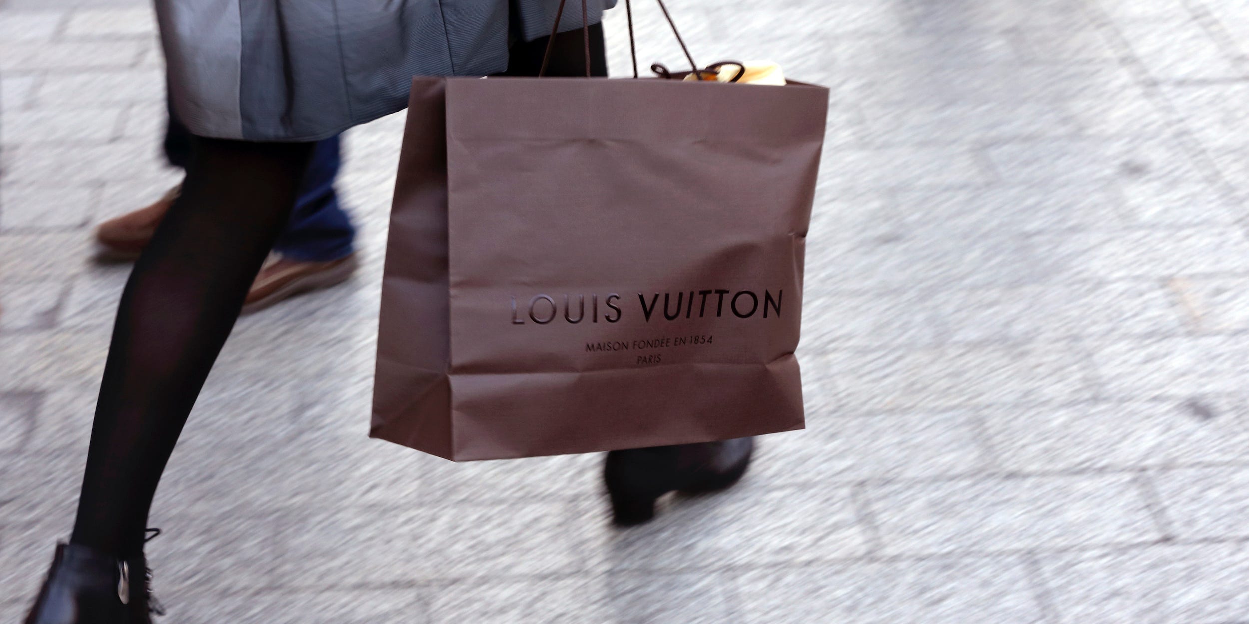 A woman walks with a Louis Vuitton shopping bag as she leaves a Louis Vuitton store in Paris September 24, 2013.