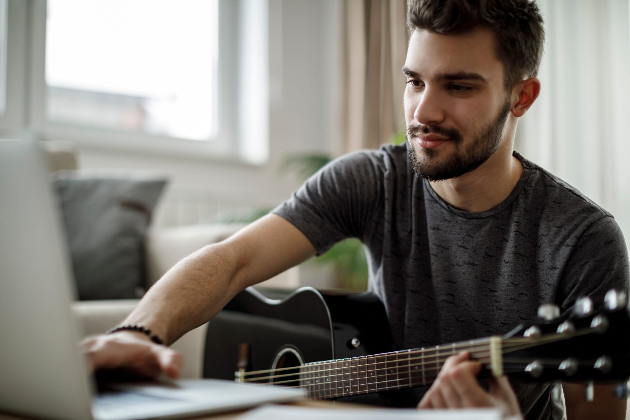 Man with guitar in front of computer