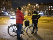 Op het Hugo de Grootplein in Amsterdam controleren agenten iemand of hij een goede reden heeft om op straat te zijn na het ingaan van de avondklok.