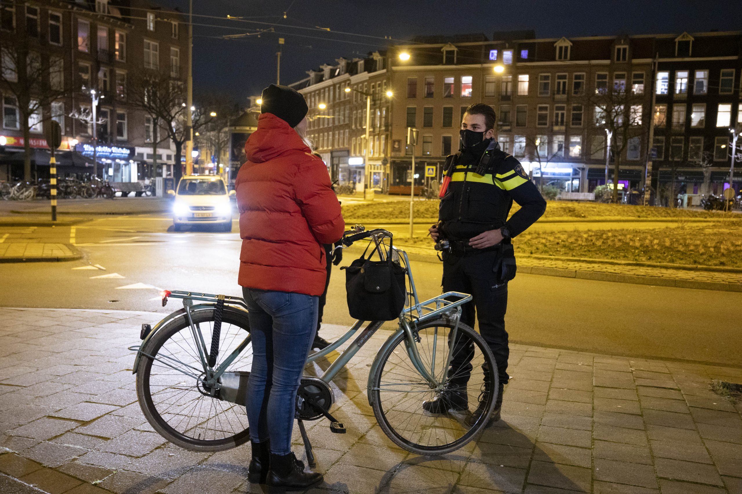 Op het Hugo de Grootplein in Amsterdam controleren agenten iemand of hij een goede reden heeft om op straat te zijn na het ingaan van de avondklok.