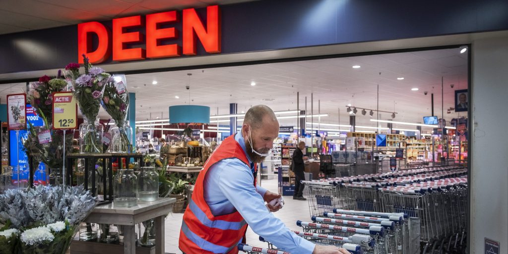 Een medewerker van supermarkt Deen maakt de winkelwagentjes schoon.
