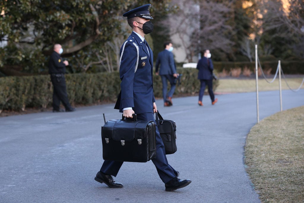 An Air Force aide carries the 'nuclear football' out of the White House as he accompanies President Joe Biden