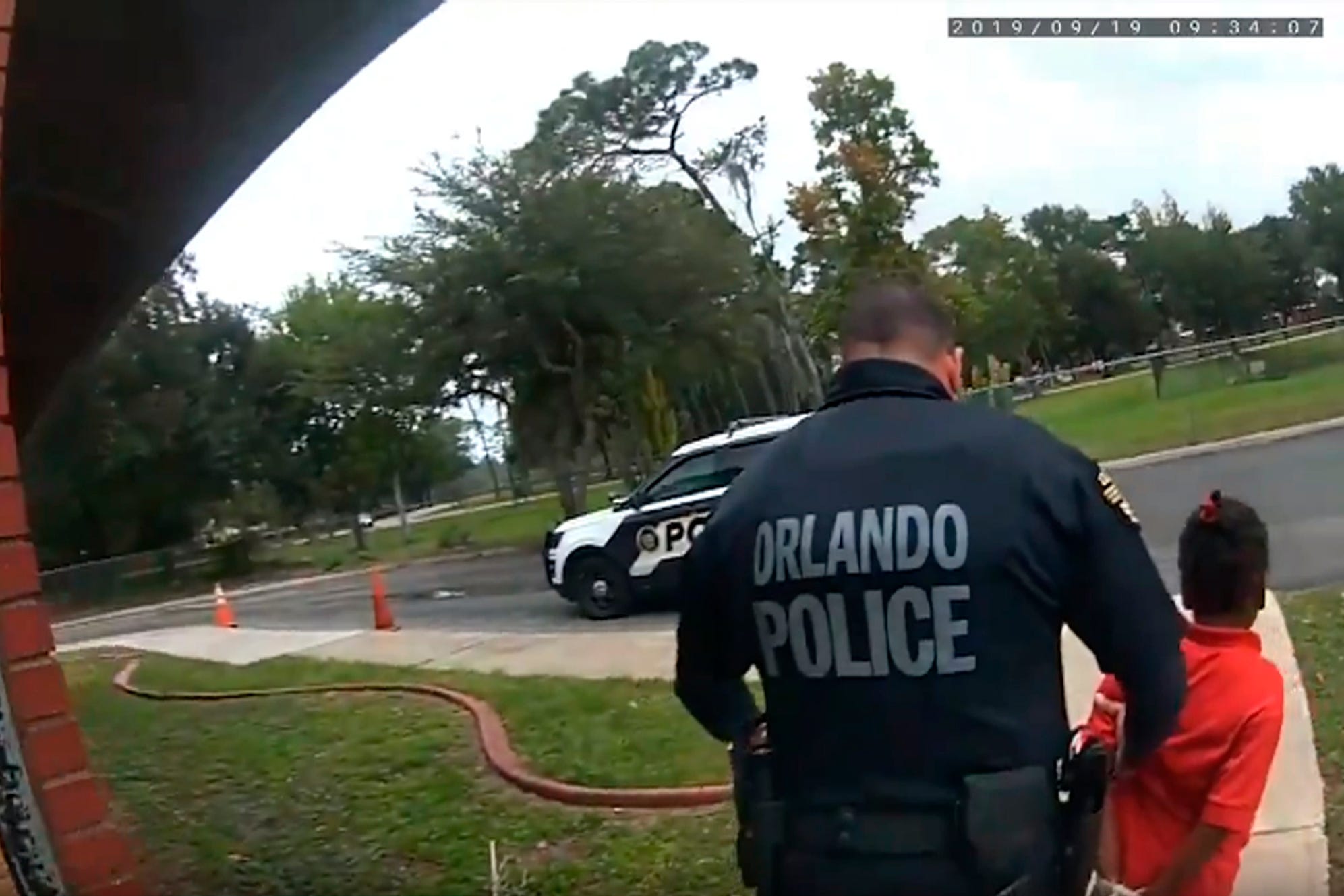 In this image taken from Sept. 19, 2019, Orlando Police Department body camera video footage, Orlando Police Officer Dennis Turner leads 6-year-old Kaia Rolle away after her arrest for kicking and punching staff members at the Lucious & Emma Nixon Academy Charter School in Orlando, Fla. Turner was fired shortly after the arrest for not getting the approval of a watch commander to arrest someone younger than 12. (Orlando Police Department/Orlando Sentinel via AP)