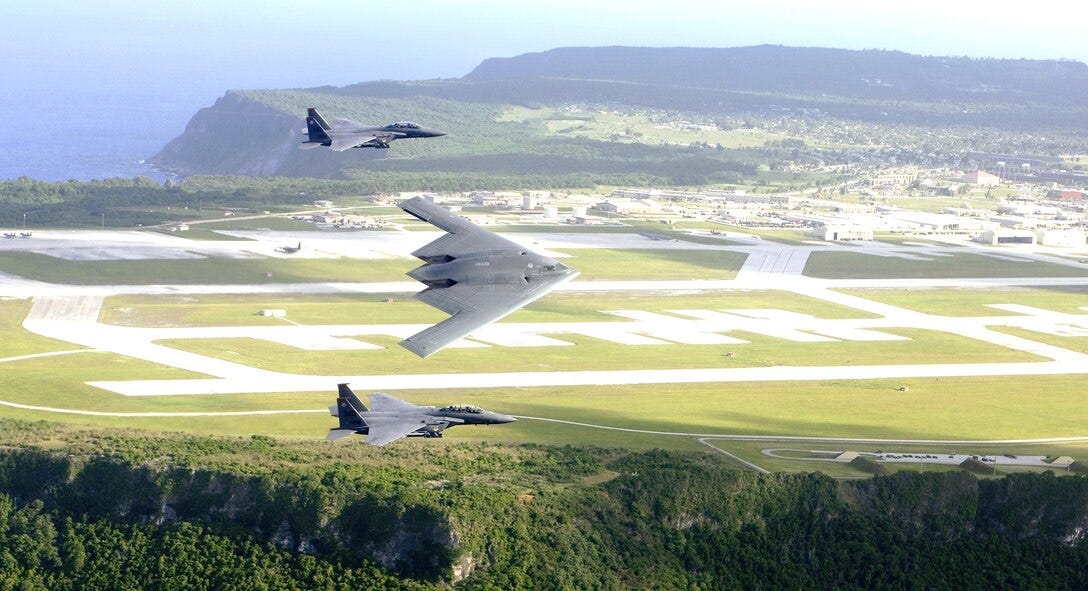 F-15E Strike Eagles and a B-2 Spirit bomber fly in formation over Andersen Air Force Base on Guam