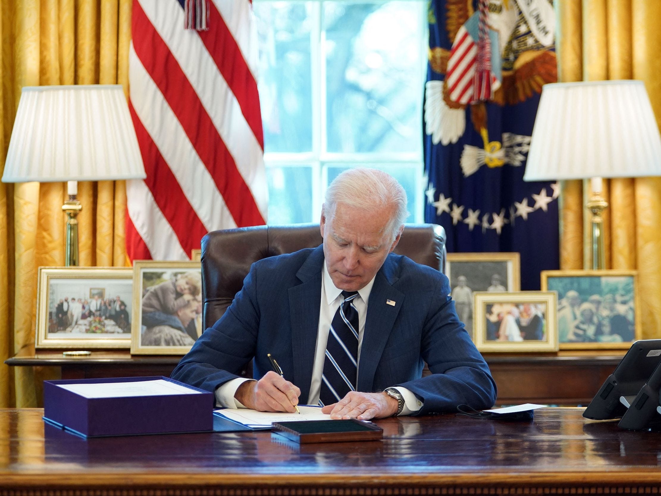 US President Joe Biden signs the American Rescue Plan on March 11, 2021, in the Oval Office of the White House in Washington, DC.