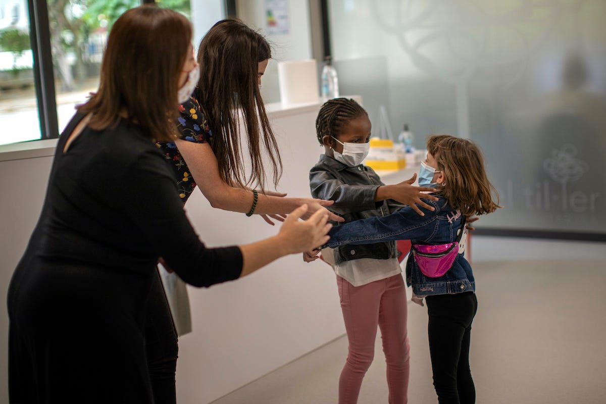 Teachers try to prevent the hug between Wendy Otin, 6, and Oumou Salam Niang, 6, as they meet during the first day of school after the lockdown.